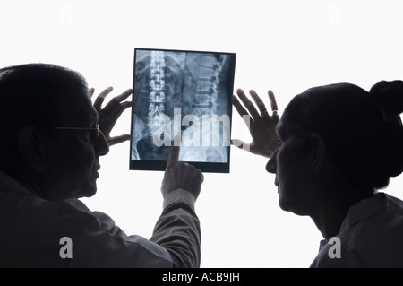 Vista posteriore di un medico di sesso maschile con un medico donna esaminando un X-Ray Foto Stock