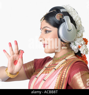 Il profilo laterale di una giovane donna che indossa le cuffie e di eseguire Bharatnatyam Foto Stock