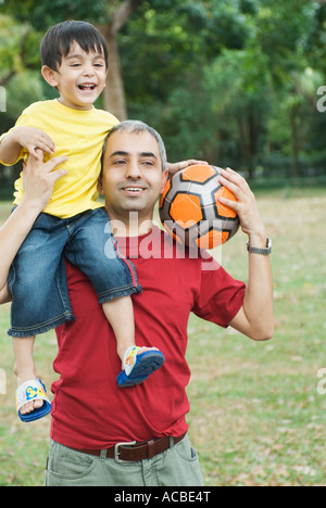 Close-up di una metà uomo adulto che porta il suo figlio sulle spalle Foto Stock