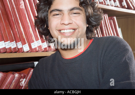 Ritratto di un maschio di studente di college in una libreria e sorridente Foto Stock