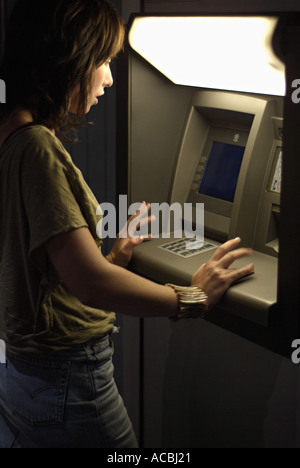 Donna ritirare denaro contante dai Bancomat di notte Foto Stock