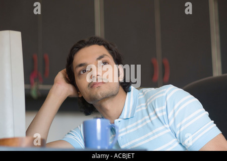 Close-up di un giovane uomo di pensiero di fronte a un computer Foto Stock