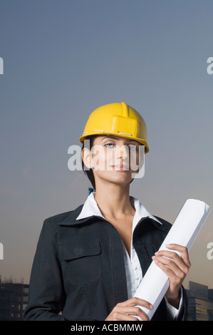 Ritratto di una imprenditrice che indossa un casco e tenendo un blueprint Foto Stock