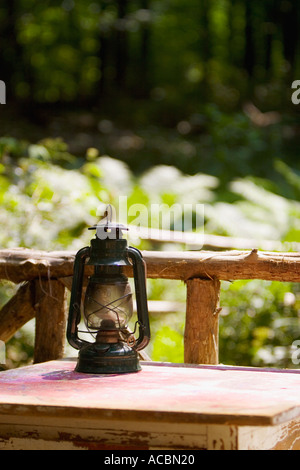 Il vecchio olio lanterna di masterizzazione sul tavolo di legno vicino rustico recinzione cedro Foto Stock
