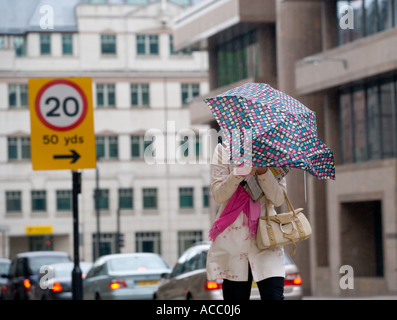 Tempo ventoso e piovoso a Londra, una donna che combatte contro il vento Foto Stock