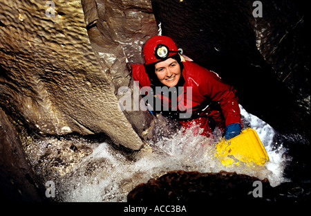 Speleologo femmina in un umido streamway grotta del Galles REGNO UNITO Foto Stock