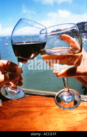 Donna e uomo con le mani in mano la tostatura la tostatura con bicchieri di vino rosso e bianco in un ristorante esterno Foto Stock