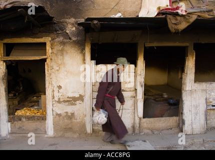 India Himalaya Jammu e Kashmir Ladakh Leh uomo locale in tradizionali panni tibetano passeggiate in città street con backery shop Foto Stock