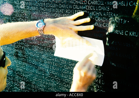 Uomo cerca per nome di eroe di guerra in Vietnam War Memorial, Washington DC, USA Foto Stock