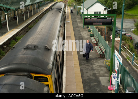 Machynlleth Powys stazione ferroviaria singolo uomo a camminare lungo la piattaforma , diesel treno DMU appena arrivati in Foto Stock