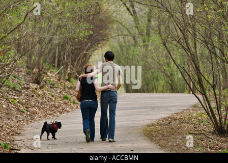 Coppia giovane con cane camminando per strada forestale Cherokee Park Louisville Kentucky Foto Stock