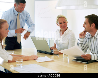 Due uomini e due donne in un ufficio avente una riunione. Foto Stock