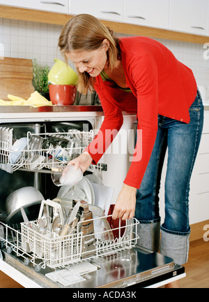 Una donna di piatti mettendo in una lavastoviglie. Foto Stock