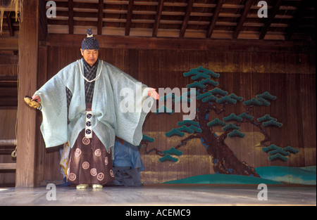 Interprete nel tradizionale costume Noh esegue una mossa durante un gioco Kyogen Foto Stock