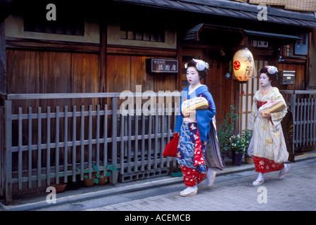 Due maiko nel quartiere di Gion di Kyoto testa fuori passato una casa da tè per un appuntamento serale Foto Stock