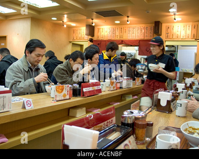 Le persone di fretta si siedono al bancone in un piccolo ristorante locale per un pranzo veloce in Giappone. Foto Stock