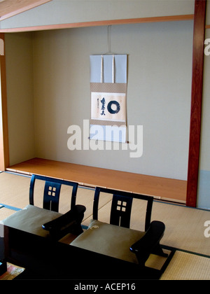 Design semplice di un interno giapponese con alcova tokonoma con pergamena appesa e cuscini zabuton su tappeti tatami in Giappone. Foto Stock