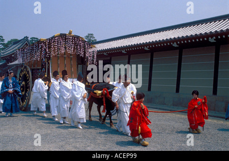 Persone che indossano costumi del periodo Heian camminano accanto al carro trainato dal bue durante il festival primaverile dell'Aoi al Palazzo Imperiale di Kyoto, Giappone. Foto Stock