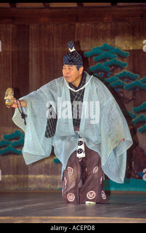 Interprete nel tradizionale costume Noh mantenendo una maschera esegue una mossa durante un gioco Kyogen Foto Stock