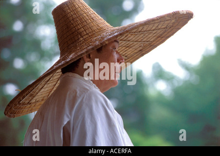 Uomo che indossa un ampio cerchio cappello di paglia durante il giorno di pioggia Foto Stock