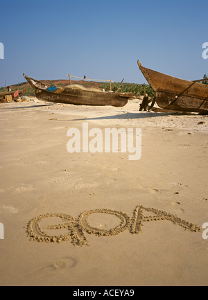 India Goa parola scritta nella sabbia da barche da pesca Foto Stock