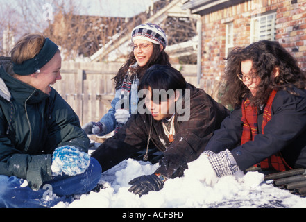 Gli adolescenti misti in America del Midwest in inverno giocare nella neve sulla sommità del trampolino Foto Stock