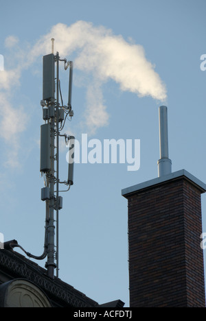 Antenna per telefono cellulare la trasmissione camino e il fumo su un tetto di casa in Zuerich, Svizzera. Foto Stock