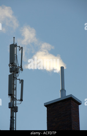 Antenna per telefono cellulare la trasmissione camino e il fumo su un tetto di casa in Zuerich, Svizzera. Foto Stock