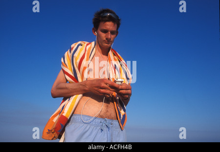 Giovane uomo in vacanza giocando con il suo ipod Foto Stock