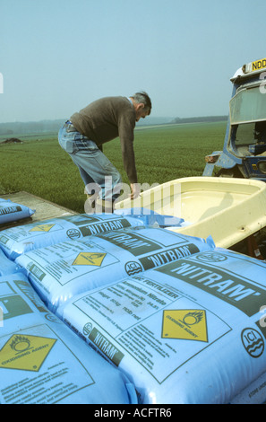 Agricoltore il riempimento di trattore montato tramoggia fertilizzante con fertilizzante di azoto Nitram ICI Foto Stock