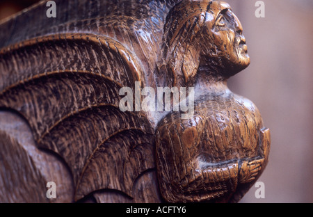 Lato vicino del piccolo scolpito in legno del XIV secolo Stallo corale figura con angeli ali e tenendo uno scudo Foto Stock