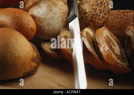 Una selezione di tipi di pane e di un coltello per pane Foto Stock