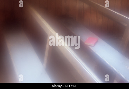 Semplice atmosferica di legno grezzo i sedili a panchina con un libro rosso a sinistra su uno e con il fasciame muri rivestiti Foto Stock