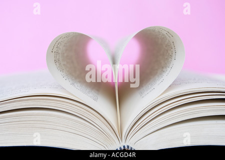 Forma di cuore costituito da pagine di libri contro un sfondo rosa Foto Stock