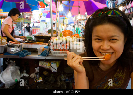 Giovane donna godendo Dukboki Chili Ricecake Outdoor Food Cart Seoul COREA DEL SUD Foto Stock