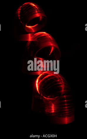 Un rosso slinky spostando in alto o in basso su sfondo nero Foto Stock