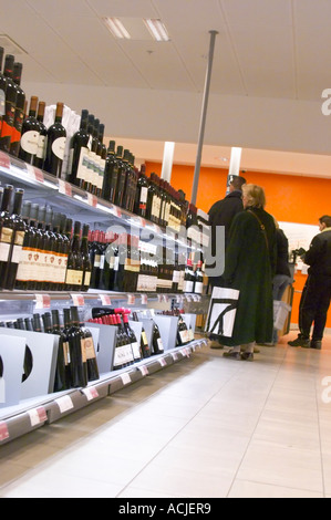 L'interno di Systembolaget, il monopolio svedese di vendita al dettaglio negozi per alcol vino birra liquori con bottiglie visualizzato sul self service ripiani. Persone in piedi in fila alla cassa in attesa di pagare. Stoccolma, Svezia, Sverige, Europa Foto Stock