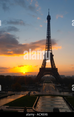 La Torre Eiffel a Parigi in inizio di mattina di alba con il sorgere del sole all'orizzonte, azzurro cielo alcune nuvole bianche e il sole giallo dorato visto dal Luogo Trocadero Parigi Francia Foto Stock