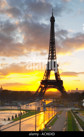 La Torre Eiffel a Parigi in inizio di mattina di alba con il sorgere del sole all'orizzonte, azzurro cielo alcune nuvole bianche e il sole giallo dorato visto dal Luogo Trocadero Parigi Francia Foto Stock