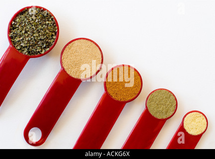 Rosso Cinque misurini da un cucchiaio per un quarto di cucchiaino di riempito con spezie su uno sfondo bianco Foto Stock