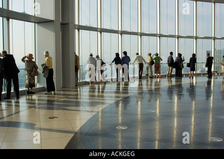 Persone di diverse forme e dimensioni che guarda foto di Windows per la vista della città dal ponte di osservazione di Tokyo City View Foto Stock