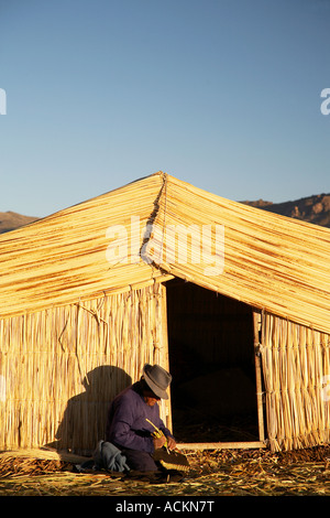 Uomo al di fuori di casa di paglia, isole galleggianti, Puno Foto Stock