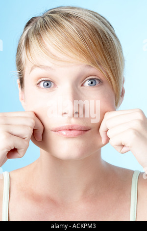 Chiudere fino a una giovane donna pizzicando la sua guance Foto Stock