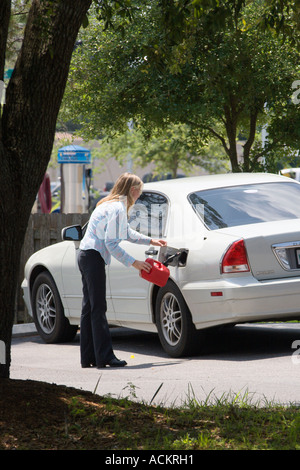 Giovane donna bionda che mette benzina in auto da una lattina di plastica portatile in Florida, Stati Uniti Foto Stock