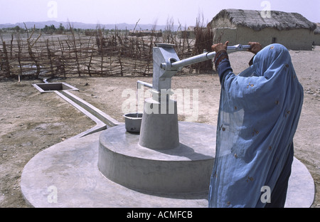 Una donna che preleva acqua da una ONG installata la pompa a mano a causa della siccità colpite provincia di Balochistan Pakistan Foto Stock