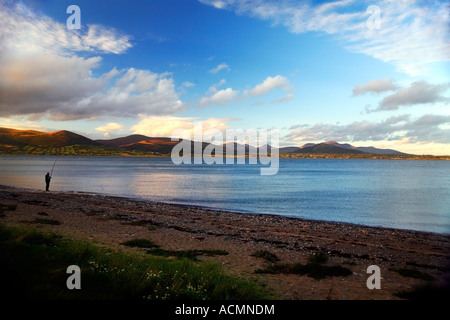 Pescatore solitario sul trefolo a Carlingford Lough Co. Louth Irlanda. La Mourne Mountains sono visibili in lontananza. Foto Stock