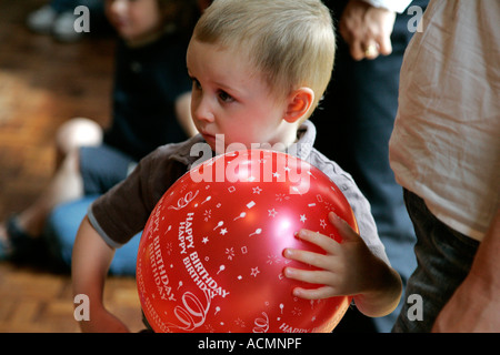 Festa di compleanno per bambini adorabile assorbita assicurato e multirazziale in background multi razziale persone compleanno torta di compleanno festa di compleanno b Foto Stock