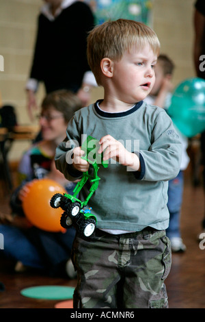 Festa di compleanno per bambini adorabile assorbita assicurato e multirazziale in background multi razziale persone compleanno torta di compleanno festa di compleanno Foto Stock