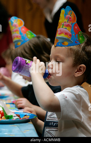 Festa di compleanno per bambini adorabile assorbita assicurato e multirazziale in background multi razziale persone compleanno torta di compleanno festa di compleanno Foto Stock