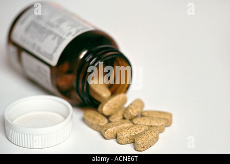 Pillola bottiglia giacente aperta su una superficie bianca con le pillole fuoriuscita. Questa immagine è stata precedentemente disponibile come immagine A65B00 o A5WFB9 Foto Stock